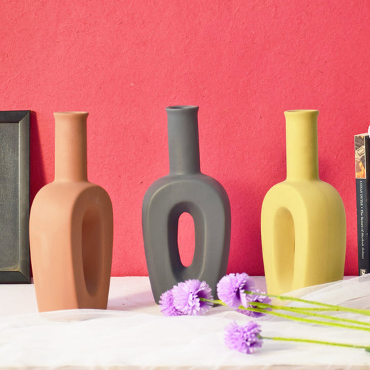Three different coloured hollow linear table vases
