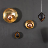 A room has three black and gold wall sconces and a hanging lamp