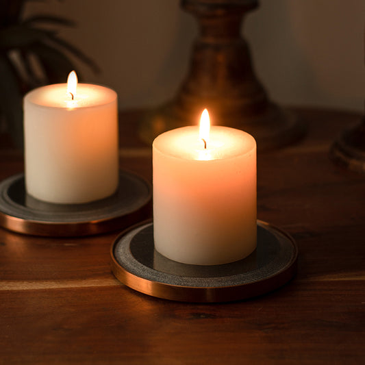 two lighted pillar candles on black candle holders