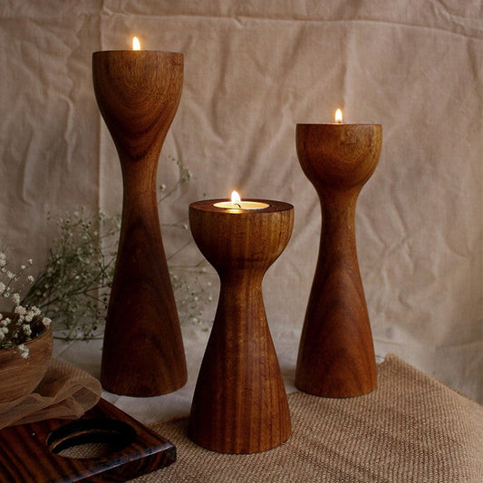 three different sized lighted tealights on wooden holders