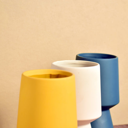 close up of three different colored pedestal vases