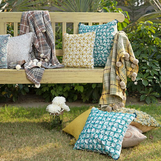 Cushions in garden with throw and white flower