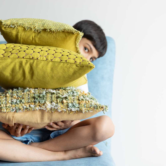 Boy holding a stack of 3 pillows