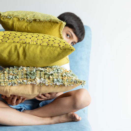 Boy holding a stack of 3 cushions